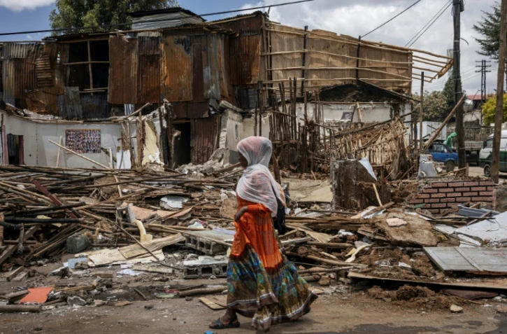 Une femme passe devant des ruines de maisons démolies dans le quartier historique de Piassa à Addis Abeba, le 14 mars 2024
