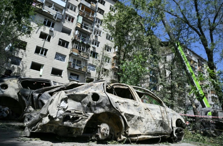Des voitures détruites devant un bâtiment résidentiel gravement endommagé  russe à Kyiv le 18 juin 2025 à la suite d'une vaste frappe de missile sur la capitale ukrainienne