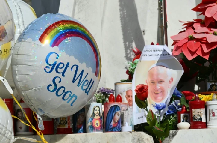 Des ballons et des bougies déposés au pied de la statue de Jean-Paul II devant l'hôpital Gemelli où est hospitalisé le pape François, le 23 février 2025 à Rome