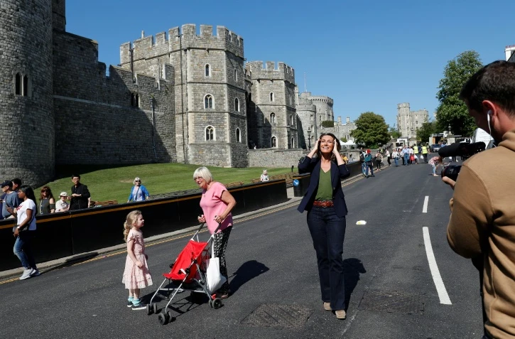 Une journaliste de TF1 marche devant le château de Windsor, à trois jours du mariage royal