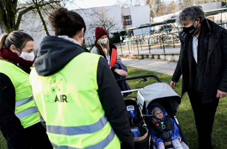 Le professeur Roeland Samson, de l'Université d'Anvers (à d.) donne des explications aux volontaires venus se promener avec Claire, une poupée équipée de capteurs pour mesurer la pollution de l'air, à Anvers (Belgique) le 25 janvier 2021.