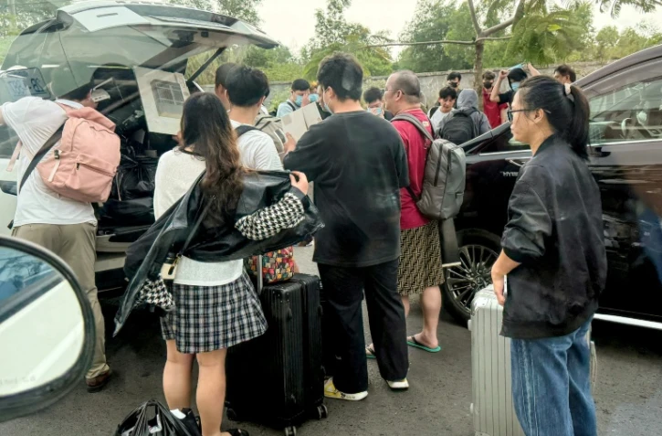 Des personnes chargent leurs bagages dans des véhicules après avoir quitté un complexe soupçonné d'être un centre d'escroquerie à Sihanoukville, le 15 janvier 2026 au Cambodge