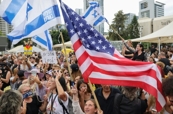 Des personnes agitent des drapeaux israéliens et américains sur la place des otages à Tel-Aviv le 9 octobre, après l'annonce d'un accord entre Israël et le Hamas