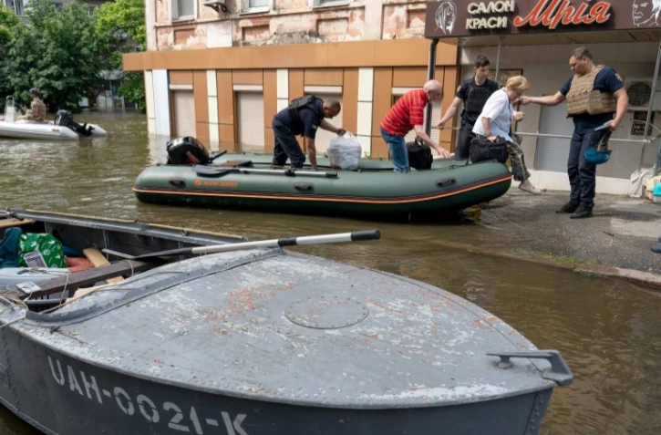 Des membres des forces de sécurité ukrainiennes évacuent des habitants d'une zone inondée à Kherson, le 8 juin 2023, après la destruction partielle du barrage de Kakhovka