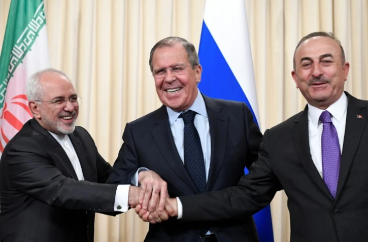 Les ministres iranien des Affaires étrangères Mohammad Javad Zarif, russe Sergueï Lavrov et turc Mevlüt Cavusoglu joignent les mains à la fin d'une conférence de presse après leurs discussions à Moscou le 28 avril 2018