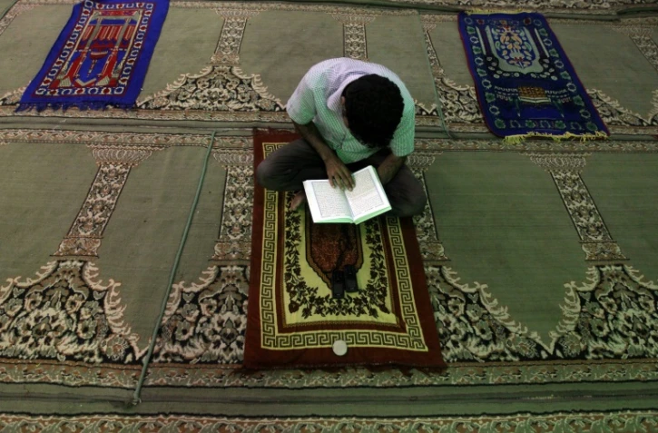 Un homme lit le Coran sur un tapis de prière dans une mosquée de Bagdad, le 16 juillet 2012