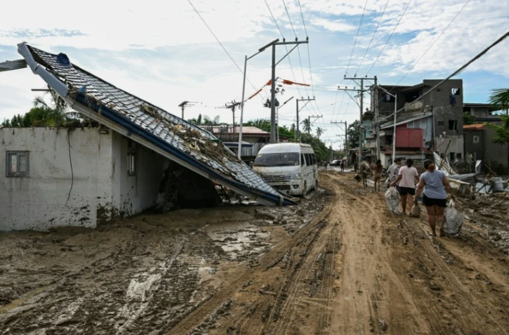 Les habitants marchent le long d'une rue couverte de boue après le passage du typhon Kalmaegi à Liloan, dans la province de Cebu aux Philippines, le 6 novembre 2025