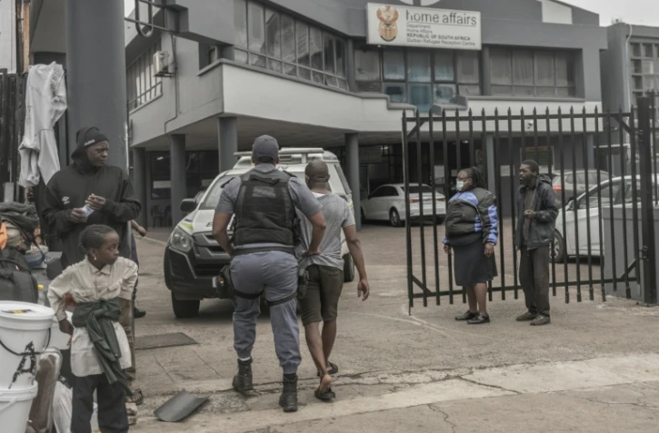 Un policier sud-africain interpelle un ressortissant étranger soupçonné d’être en situation irrégulière lors d’une opération de contrôle et de fouille dans le centre de Durban, le 29 juin 2026