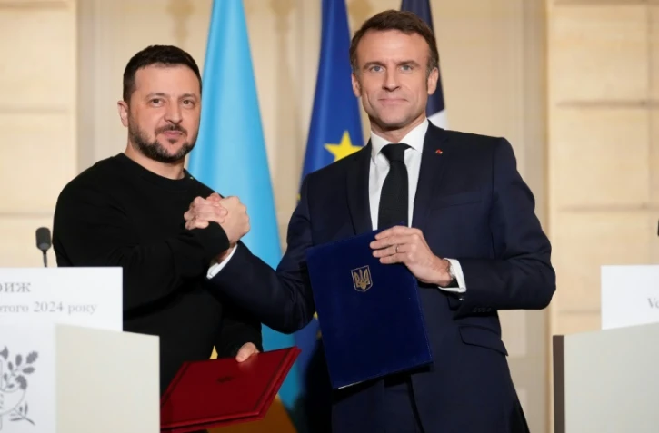 Le président français Emmanuel Macron (droite) et son homologue ukrainien Volodymyr Zelensky se serrent la main, le 16 février 2024 à Paris