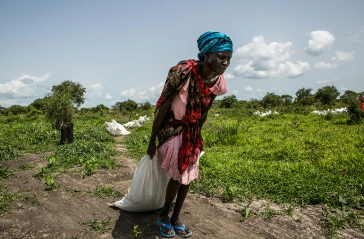 Au Soudan du Sud, une femme ramasse un sac de céréales distribué par le Programme alimentaire mondial, en juillet 2018