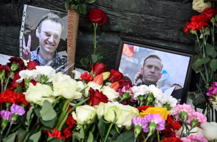 Des photos de l'opposant Alexeï Navalny sont exposées près de fleurs déposées au niveau du monument pour les victimes des répressions politiques, le 17 février 2024 à Moscou