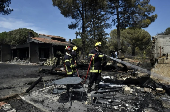 Un pompier arrose les décombres d'une maison détruite par un incendie, le 15 août 2023 à Saint-André, près d'Argelès-sur-Mer, dans les Pyrénées-Orientales