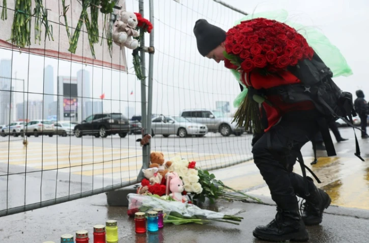 Une femme dépose des fleurs devant un mémorial de fortune devant la salle Crocus, un jour après une attaque sanglante, à Krasnogorsk, près de Moscou, le 23 mars 2024
