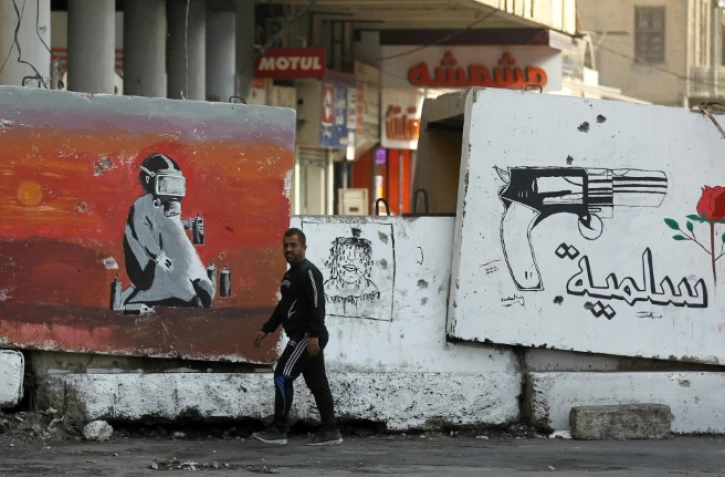 Un homme passe devant de grandes dalles de béton bloquant une rue de Bagdad, le 25 décembre 2019