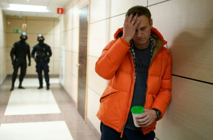 L'opposant russe Alexeï Navalny et deux policiers en arrière-plan, dans un couloir d'un centre d'affaires qui héberge son organisation anti-corruption, le 26 décembre 2019 à Moscou