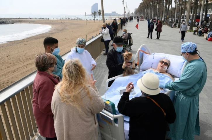 Une patiente hospitalisée à l'hôpital del Mar à Barcelone est sortie par des amis et du personnel médical pour prendre l'air près d'une plage, à Barcelone, le 4 mars 2021. 