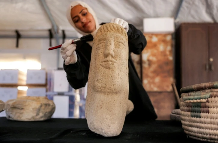 Une membre de l'association Mayasem pour la culture et les arts nettoie un artefact à la brosse, sous une tente à Khan Younès, dans le sud de la bande de Gaza, le 11 juillet 2026