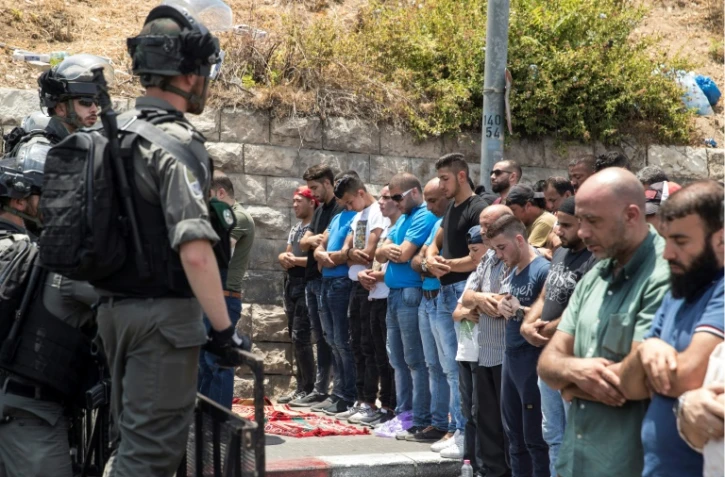 Des soldats israéliens montent la garde alors que des palestiniens prient dans la rue, près de la vieille ville de Jérusalem, le 21 juillet 2017
