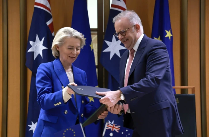 La présidente de la Commission européenne Ursula von der Leyen et le Premier ministre australien Anthony Albanese échangent des copies de l'accord commercial Australie-UE, le 24 mars 2026 à Canberra