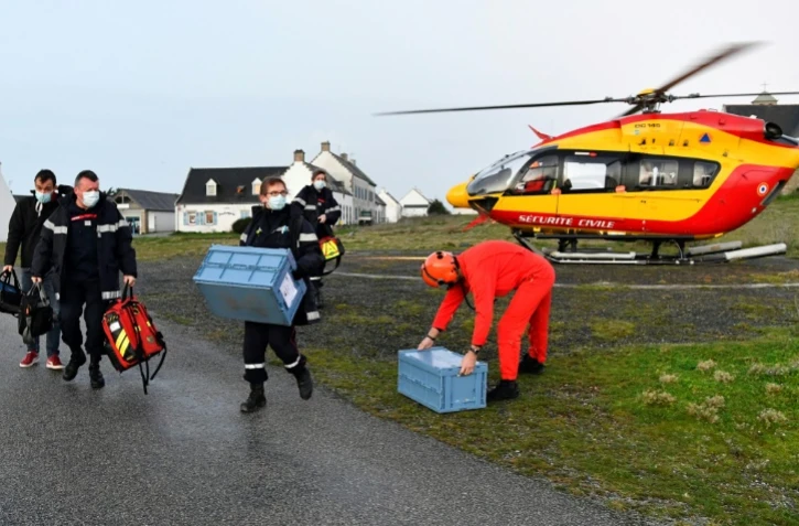 Des soignants du Service départemental d'incendie et de secours arrivent en hélicoptère avec deux caisses contenant des vaccins anti-Covid-19 sur l'île de Hoëdic (Morbihan), le 29 janvier 2021