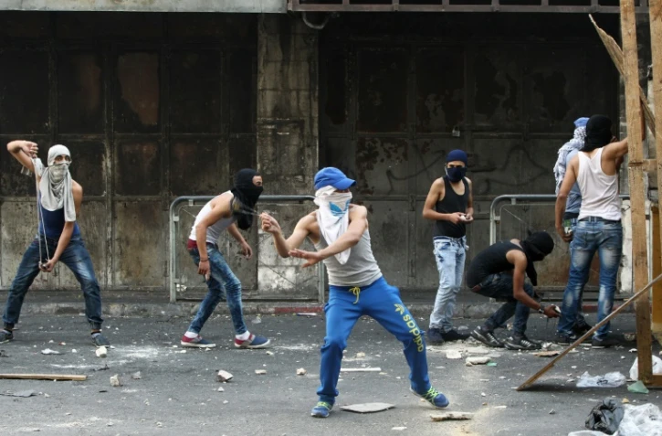 Des jeunes Palestiniens lancent des pierres sur les forces de sécurité israéliennes lors de heurts à Hébron, le 4 octobre 2015