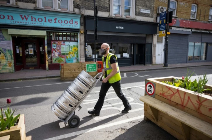 Un homme livre de la bière dans un pub de Londres en prévision de l'allègement des restrictions sanitaires le 9 avril 2021