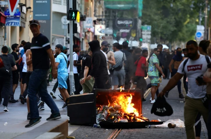 De manifestants marchent près d'une poubelle en feu durant des affrontements avec la police à Marseille, le 1er juillet 2023