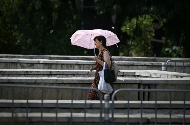 Une femme sous un parasol dans le centre de Sofia, pendant une canicule, le 18 juillet 2024