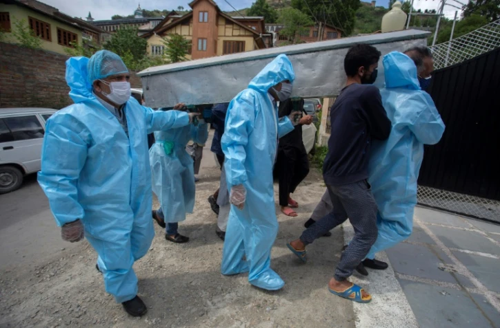Des proches revêtus de combinaisons de protection portent le corps d'une victime du coronavirus lors de funérailles à Srinagar, Inde, le 7 mai 2021
