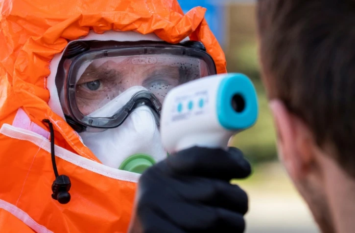 Un fonctionnaire polonais vérifie la température de Polonais qui franchissent la frontière, en direction de leur pays natal, à Francfort-sur-Oder, le 16 mars 2020