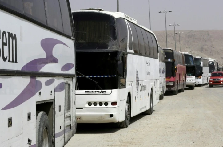 Des bus affrétés par le régime syrien attendent des rebelles ayant accepté de quitter la localité de Harasta dans la Ghouta orientale, près de Damas, le 22 mars 2018