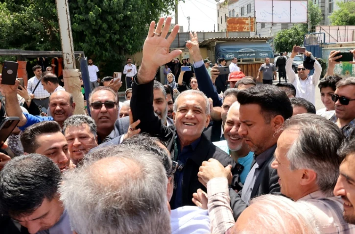 Le candidat réformateur pour la présidentielle iranienne, Massoud Pezeshkian (C), le 5 juillet 2024 au milieu de partisans devant un bureau de vote à Téhéran