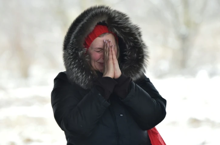 Une femme attend ses proches qui traversent un pont détruit pour évacuer la ville d'Irpin en Ukraine le 8 mars 2022