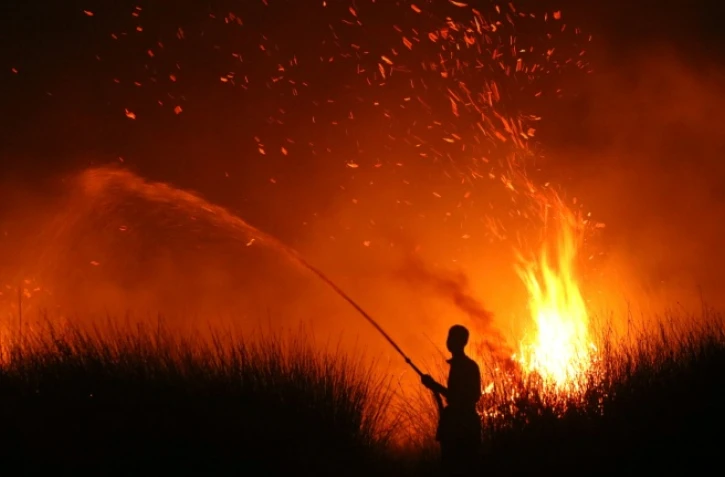 Cette photo prise le 11 août 2026 montre la silhouette d'un villageois tentant d'éteindre un incendie de forêt à Palangkaraya, dans le centre de l'Indonésie