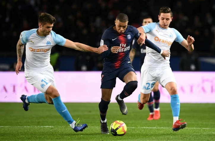 L'attaquant du PSG Kylian Mbappé entre les joueurs de l'OM Duje Caleta-Car (g) et Florian Thauvin (d) en championnat, le 17 mars 2019 au Parc des Princes