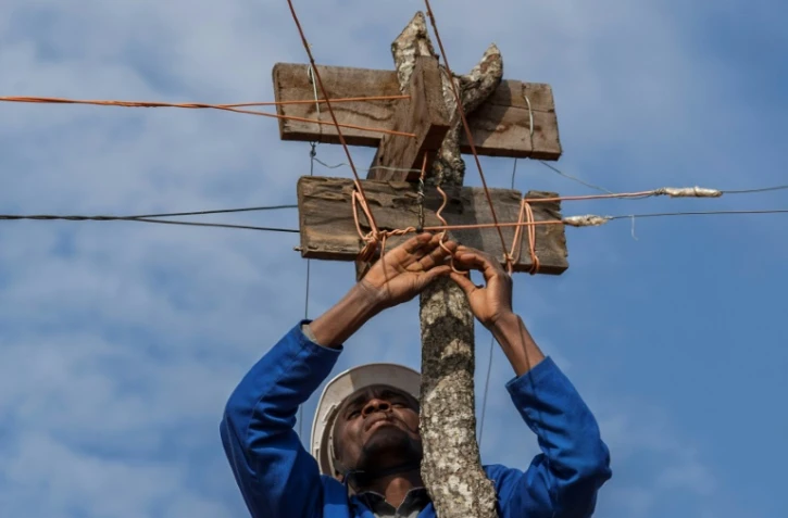 Electricien autoditacte, Colrerd Nkosi contrôle le 23 août 2021 la ligne électrique qui alimente son village de Yobe Nkosi, dans le Nord du Malawi, depuis une petite centrale hydro-électrique artisanale qu'il a installée