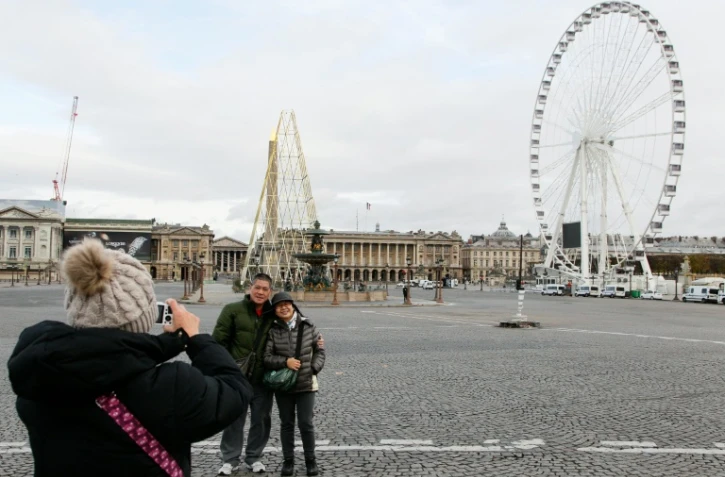 Des touristes prennent la pose devant la place de la Concorde à Paris le 30 novembre 2015