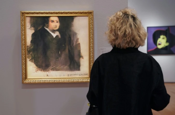 Une femme admire le "Portrait d'Edmond de Belamy" créé par le collectif français Obvious via un logiciel d'intelligence artificielle, le 22 octobre 2018 chez Christie's à New York
