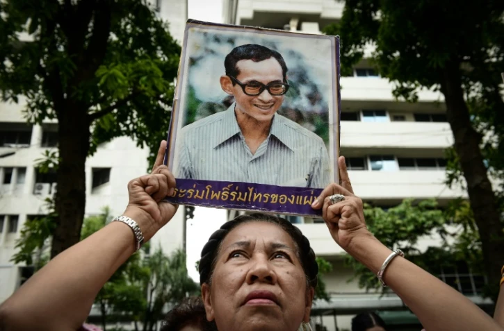 Une Thaïlandaise brandit le portrait du roi de Thaïlande Bhumibol Adulyadej et prie pour son rétablissement devant l'hôpital de Bangkok, où le souverain est soigné, le 12 octobre 2016
