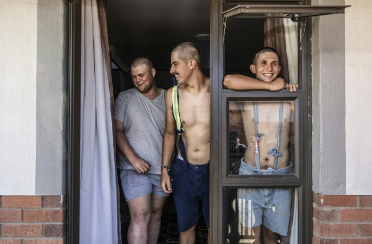 Des étudiants, Belly Sharpe (C), 18, et Eben Mans (D), 20, rient avec un ami à l'entrée de leur dortoir Vaalbos dans l'enclave afrikaner d'Orania en Afrique du Sud, le 28 janvier 2026.