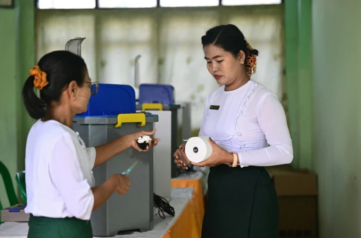 Des membres de la commission électorale de Birmanie installent des machines de vote électronique dans un bureau de vote, à Rangoun, le 24 janvier 2026
