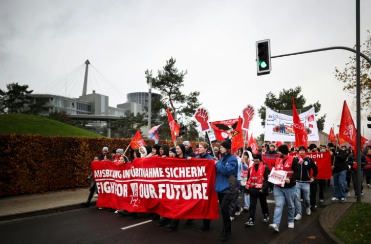 Des employés du constructeur automobile allemand Volkswagen déploient une banderole portant l'inscription "Fight for our Future" lors d'une manifestation à l'usine Volkswagen de Wolfsburg, dans le nord de l'Allemagne, le 21 novembre 2024