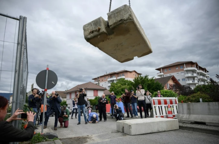 Journalistes et passants observent l'opération de retrait d'un bloc de béton qui fermait la frontière entre France et Suisse, le 14 juin 2020 à Thonex, en France