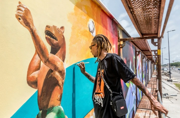 L'artiste brésilien Edgar Bernardo Dos Santos (Ed-Mun) réalise une fresque murale, pendant le festival Effet Graff, le 18 mai 2022 à Cotonou, au Bénin