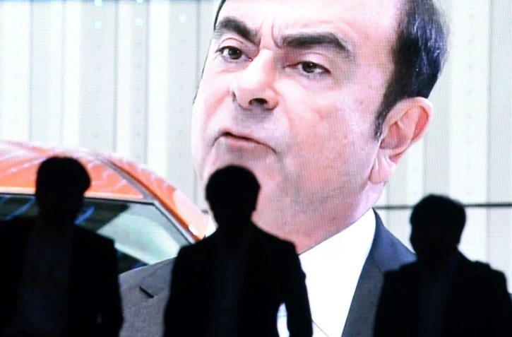 Des personnes marchent devant une photo de Carlos Ghosn, le PDG de l'alliance Renault-Nissan-Mitsubishi Motors, à Tokyo le 20 novembre 2018
