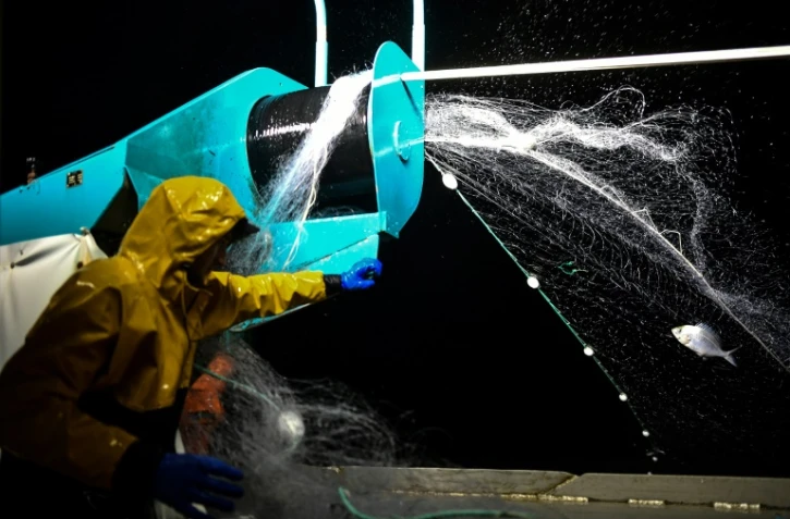 Un pêcheur lance ses filets, au large de La Rochelle, le 21 février 2024, alors que la pêche dans le golfe de Gascogne a repris après une interdiction d'un mois
