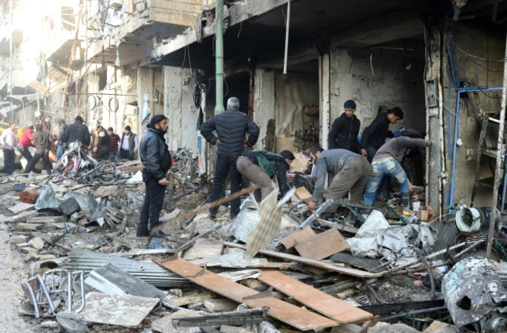 Des habitants au milieu des décombres d'immeubles après des frappes aériennes, le 4 décembre 2016 à Maaret al-Noomane, en Syrie