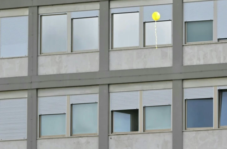 Un ballon jaune vole devant les fenêtres de l'hôpital  Gemelli de Rome, où le pape François est hospitalisé, le 16 mars 2025