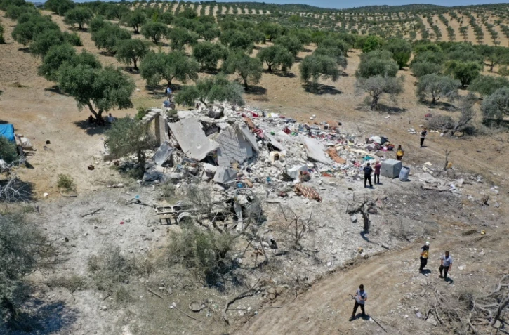 Des Syriens autour des décombres d'une maison à la suite d'une frappe aérienne russe à la périphérie de la ville de Jisr al-Shughur, tenue par les rebelles, dans la province d'Idlib, le 22 juillet 2022