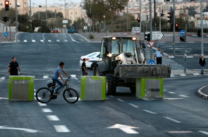 Un policier israélien monte la garde au moment où les forces de sécurité israéliennes installent des blocs de ciments sur une route séparant Jérusalem-est et Jérusalem-ouest le 11 octobre 2016 